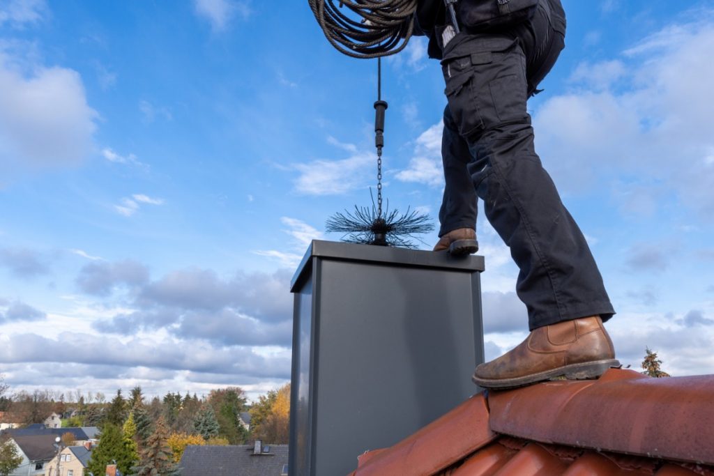 What Should You Know Before Hiring A Professional Chimney Cleaning   Chimney Sweep Cleaning A Chimney Standing On The House Roof Lowering Picture Id1284524676 1024x683 